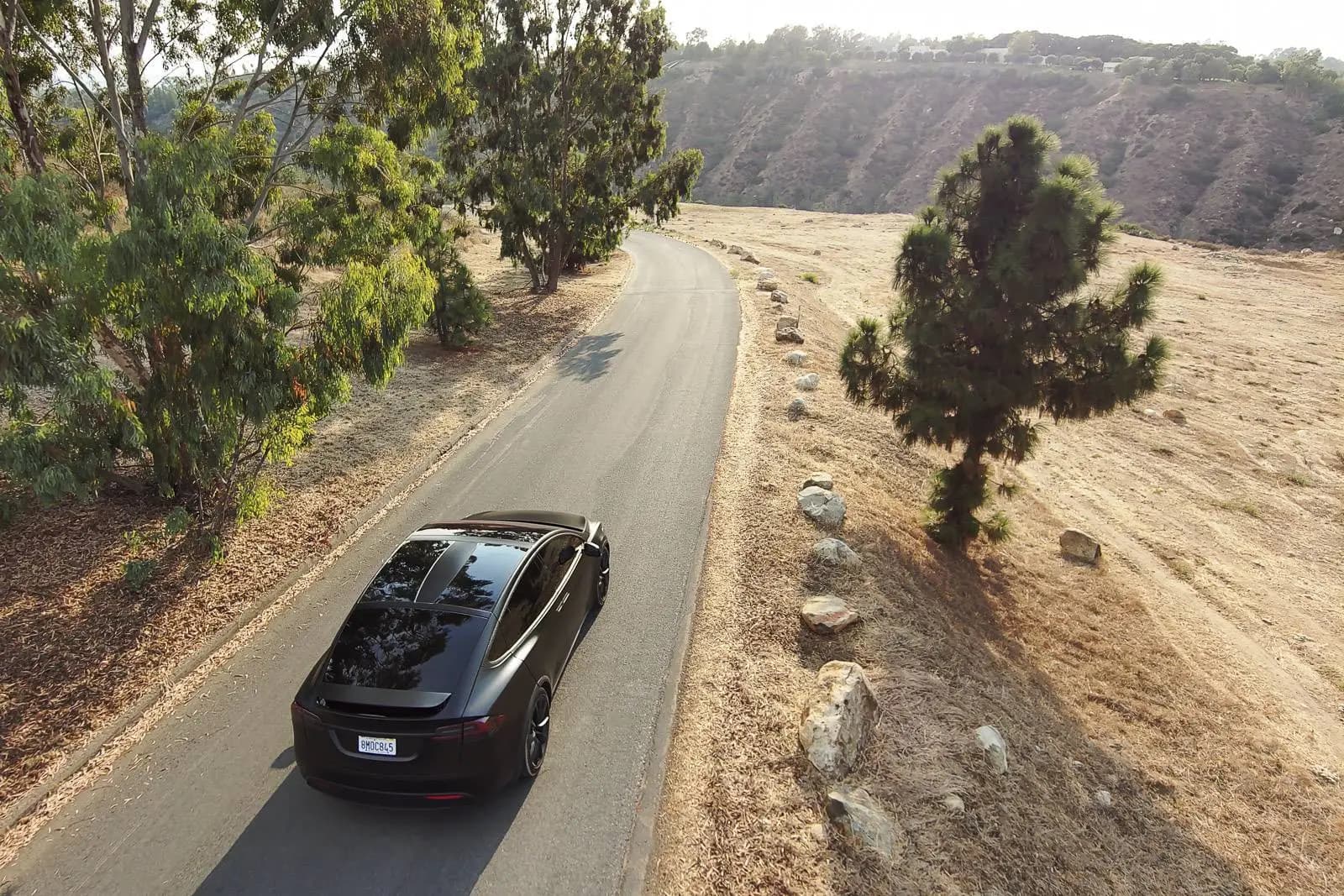 Matte-black Tesla Model X with Kavaca IR window film on an open road